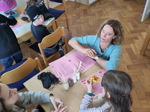 Workshop-Leiterin und zwei Kinder am Tisch