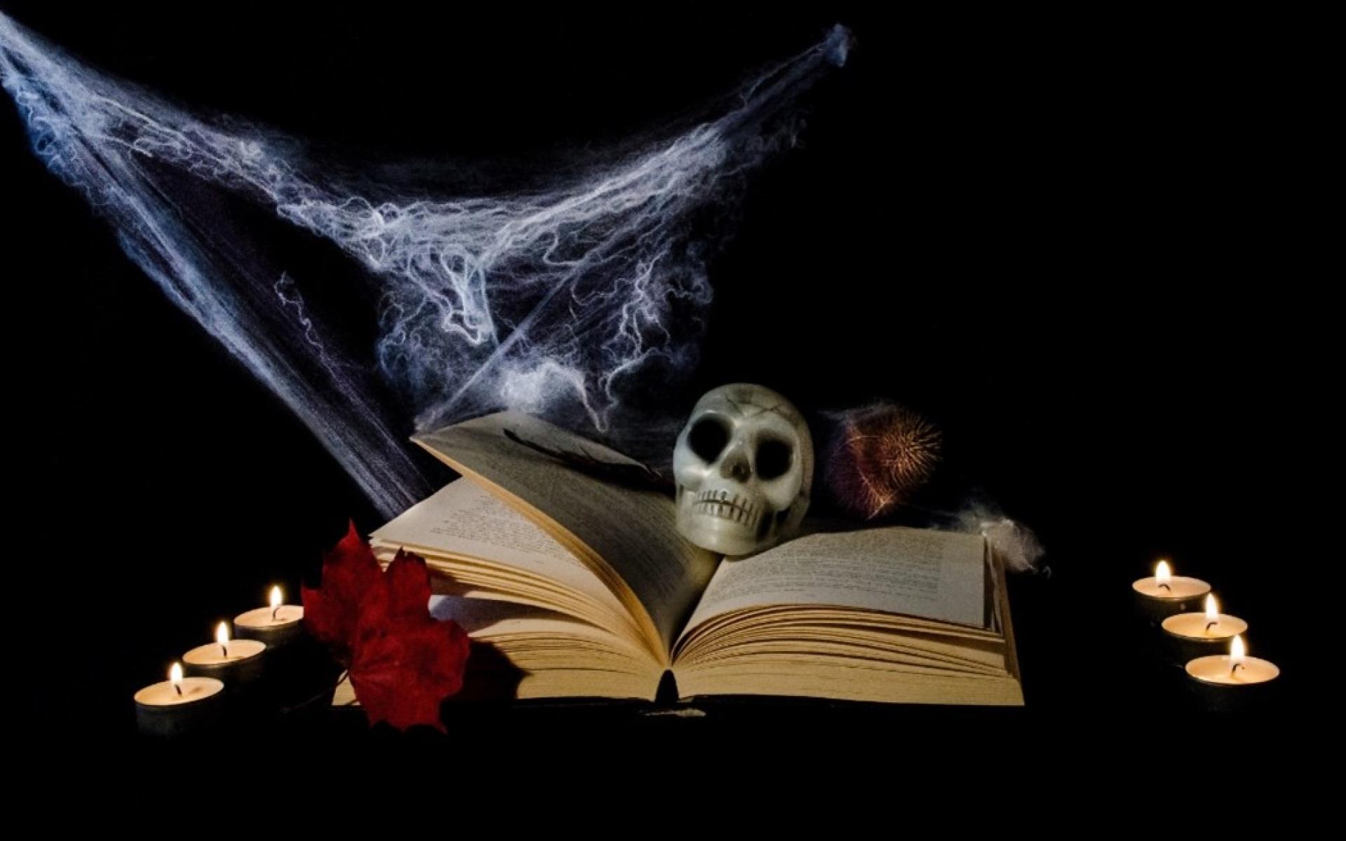Aufgeschlagenes Buch mit Totenschädel, Spinnweben und von Kerzen umgeben